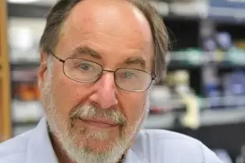 David Baltimore smiling with his lab in the background.