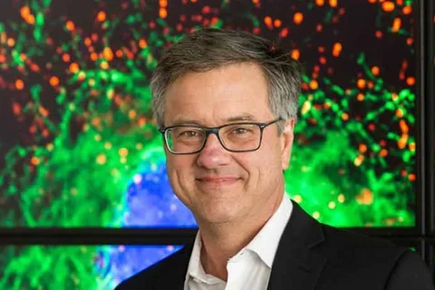 Dr. Jeff F. Miller smiling with television in the background.