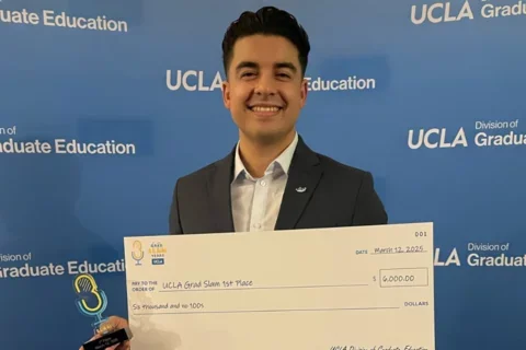 MIMG Graduate Student Pablo Alvarez smiling and holding 1st place winner check. 
