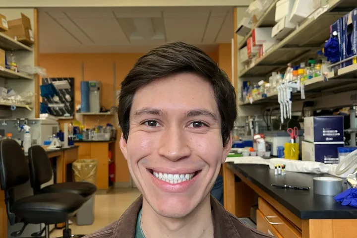Christian Bustillos smiling with lab in the background. 