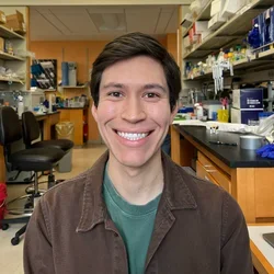 Christian Bustillos smiling with lab in the background. 