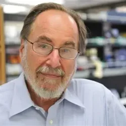 David Baltimore smiling with his lab in the background.