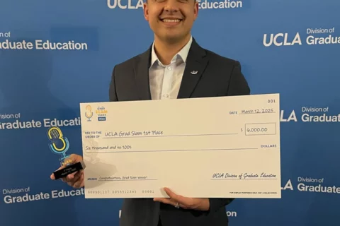 MIMG Graduate Student Pablo Alvarez smiling and holding 1st place winner check.